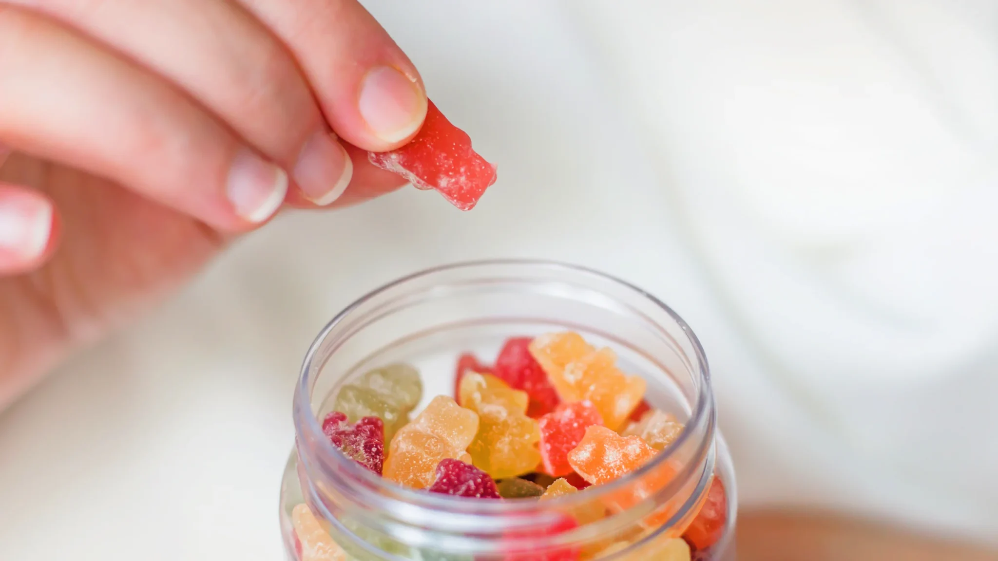 A variety of colorful gummy supplements in different shapes spilling from a bottle onto a clean surface, showcasing the appeal of the modern wellness industry.