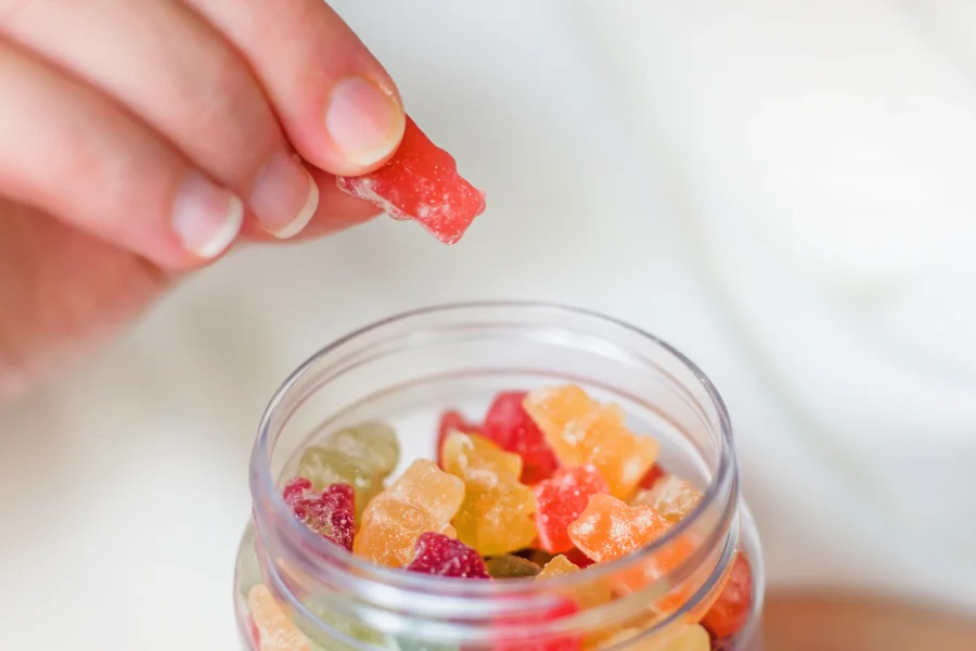 A variety of colorful gummy supplements in different shapes spilling from a bottle onto a clean surface, showcasing the appeal of the modern wellness industry.
